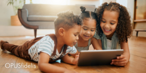 3 kids looking at a tablet on the floor