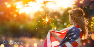 A girl wrapped in an American flag holds a sparkler
